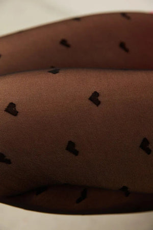 Close-up detail of sheer black 20DEN fashion tights showing a delicate black love heart pattern on the skin.