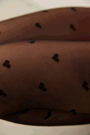Close-up of sheer black tights with a small heart pattern.