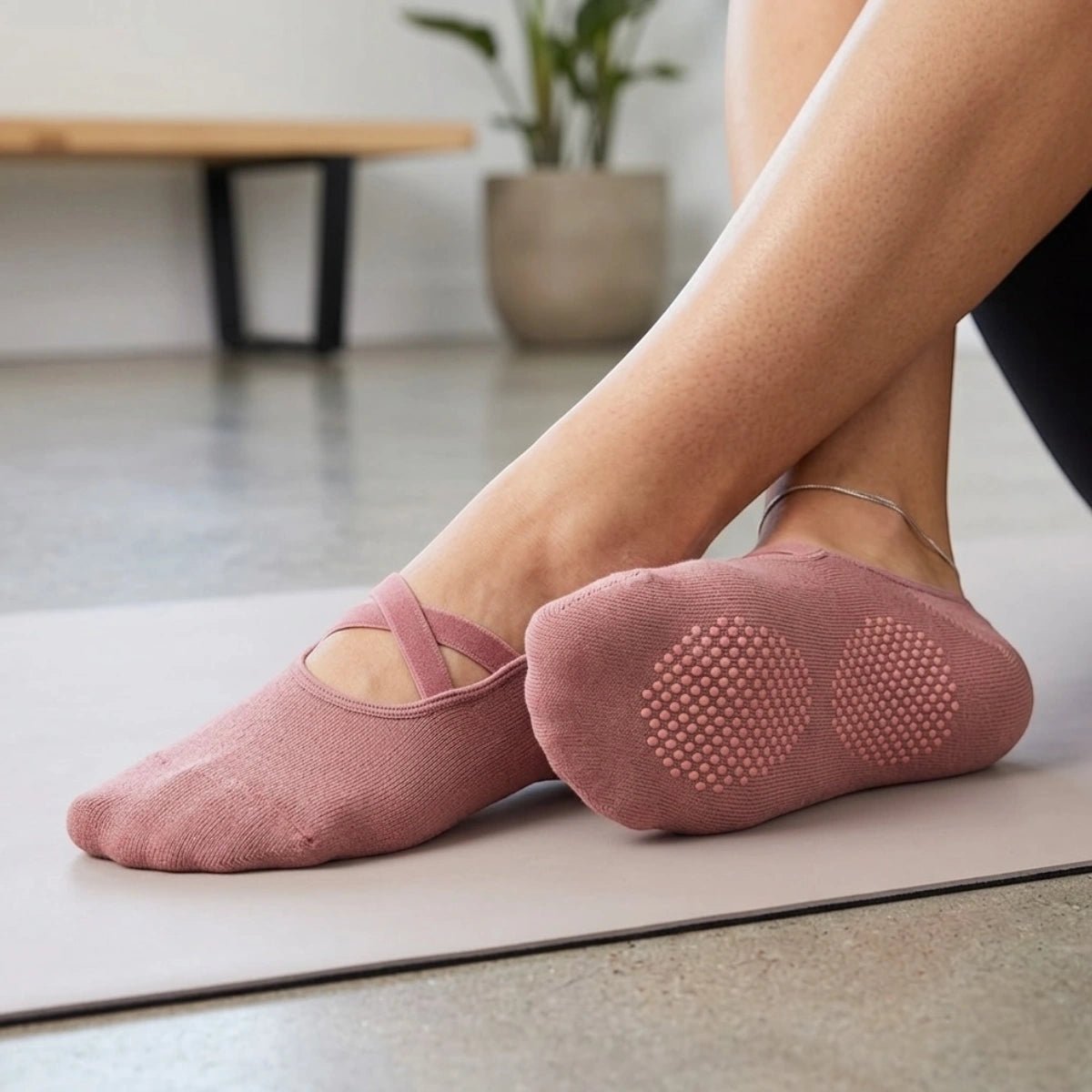 A person wearing rose coloured yoga socks with criss cross band and anti-slip sole