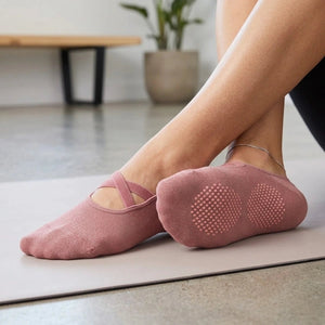 A person wearing rose coloured yoga socks with criss cross band and anti-slip sole
