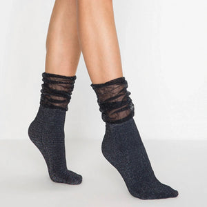 Image of woman's feet wearing black and silver sparkled socks with loose fitting cuff