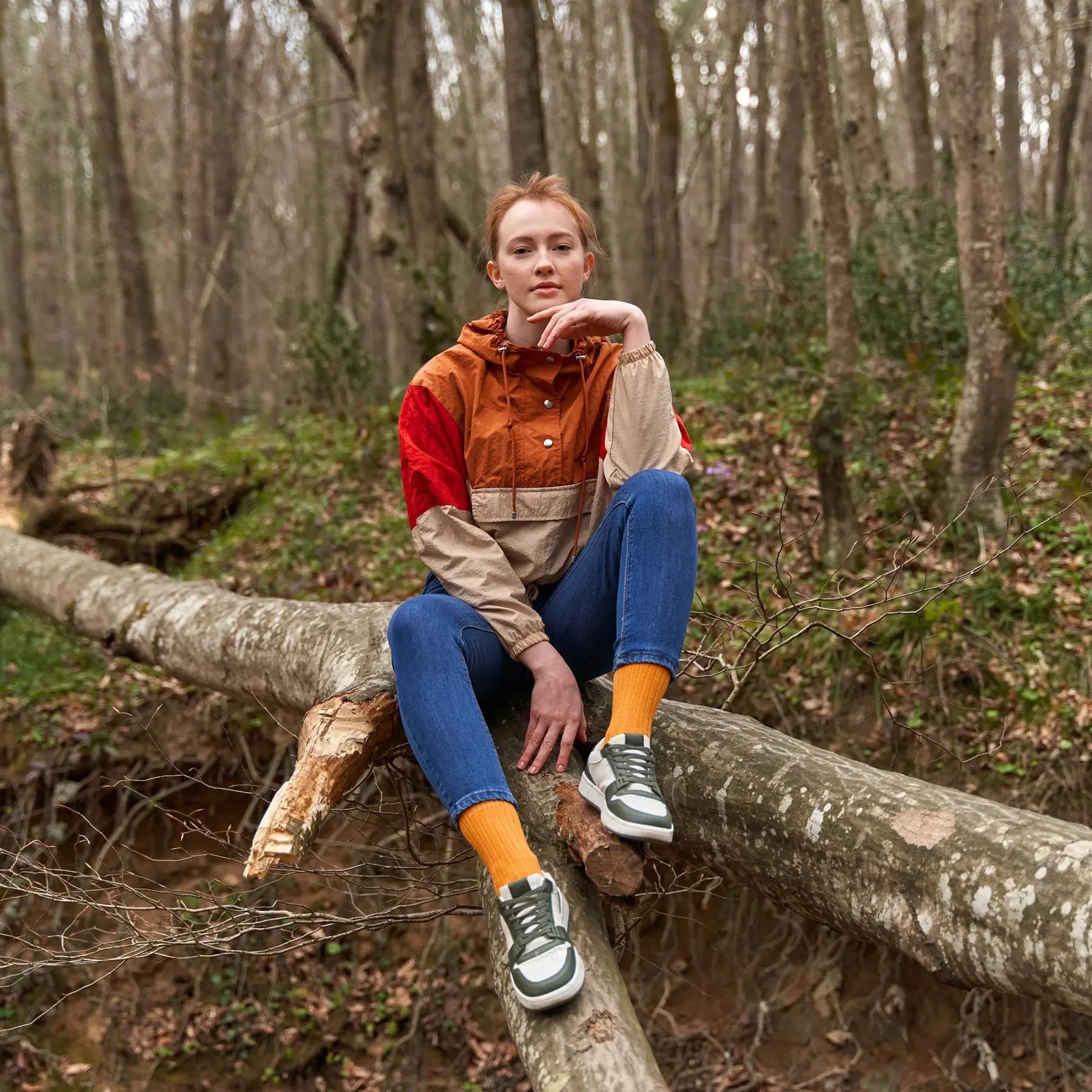 Person wearing orange bio-cotton socks sitting on a tree trunk