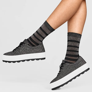 person wearing black and silver striped crew socks wearing stylish sneakers