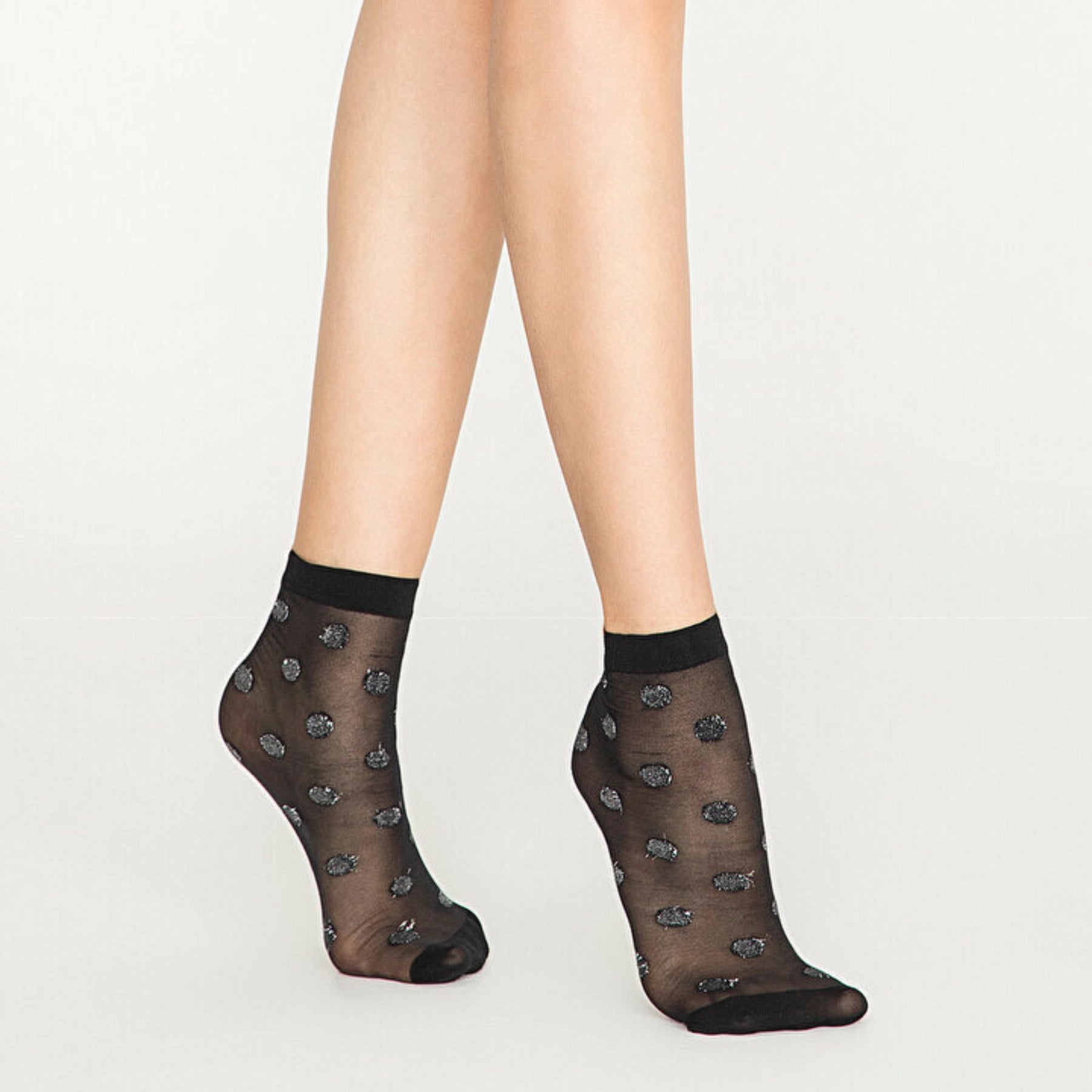 Person wearing sheer black ankle socks with silver dots