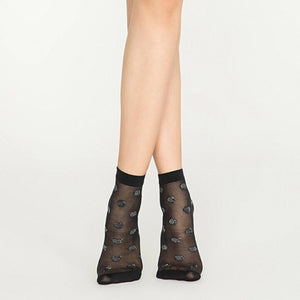 Person wearing sheer black ankle socks with silver dots