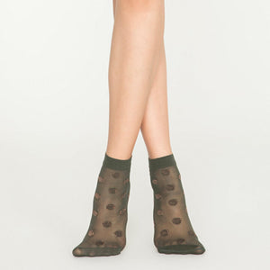 Person wearing sheer khaki ankle socks with rose gold dots