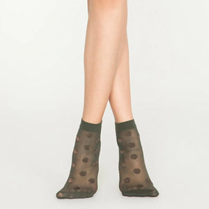 Person wearing sheer khaki ankle socks with rose gold dots