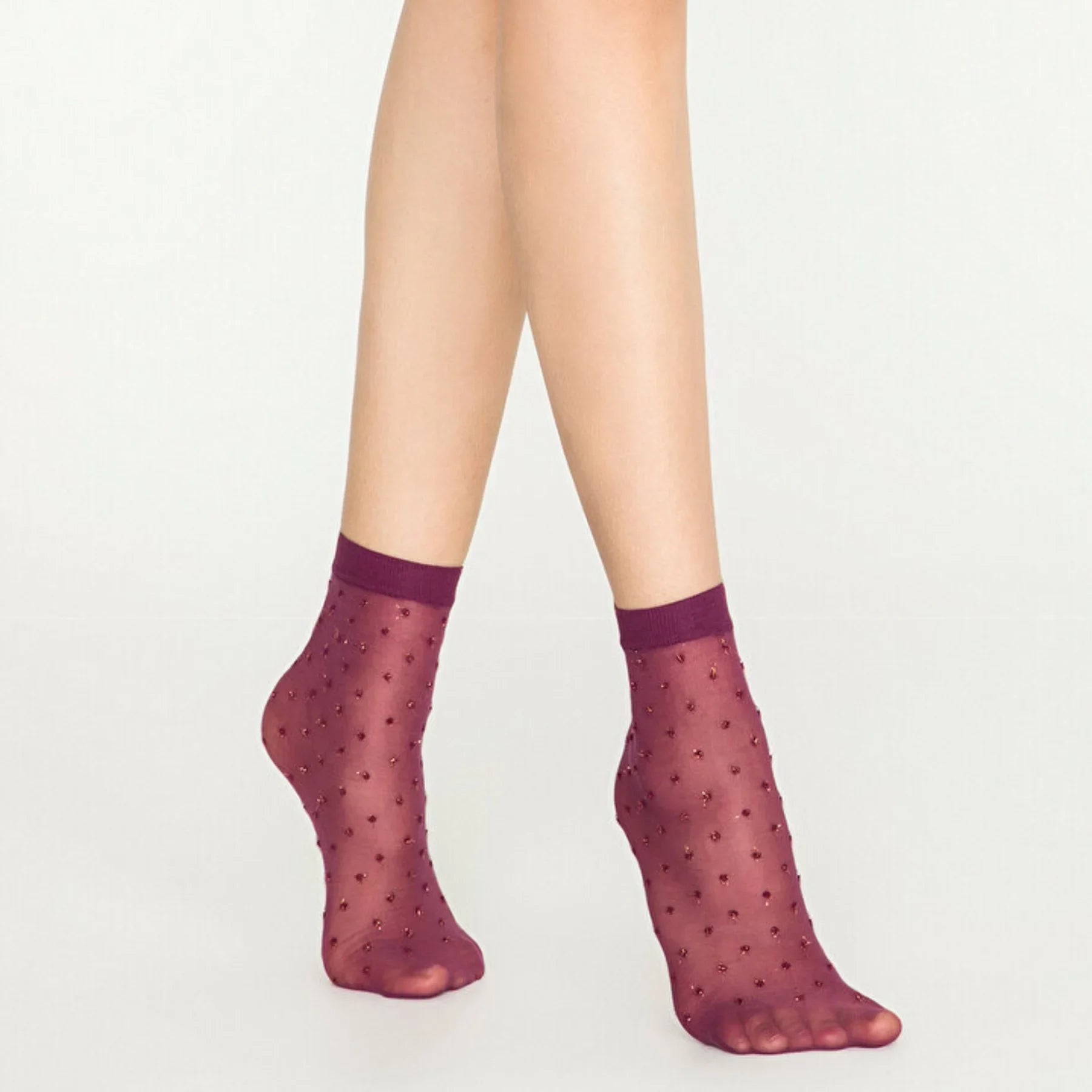 Woman wearing sheer amethyst ankle socks with gold dots on white background