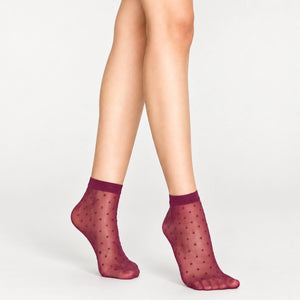Woman wearing sheer amethyst ankle socks with gold dots on white background