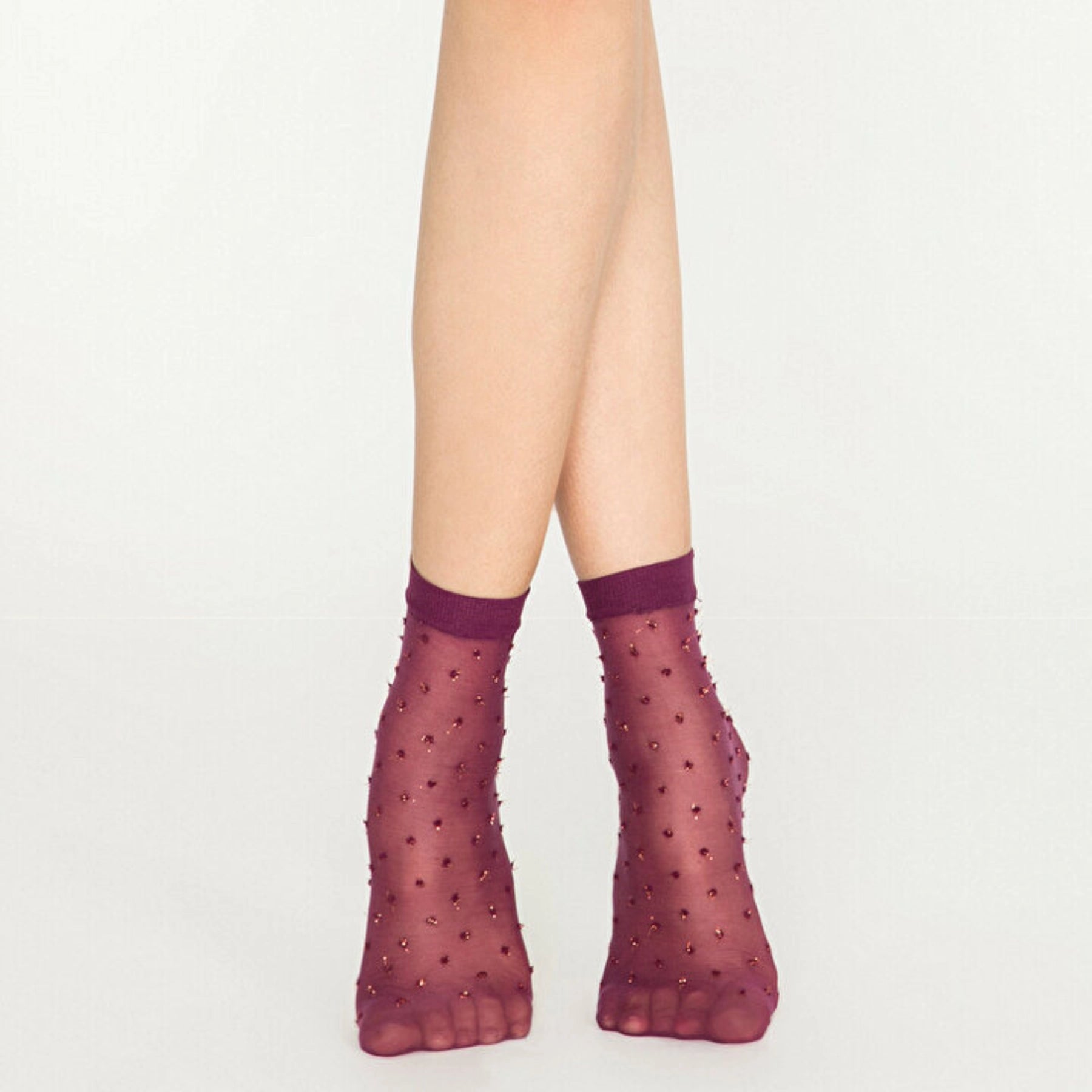 Woman wearing sheer amethyst ankle socks with gold dots on white background
