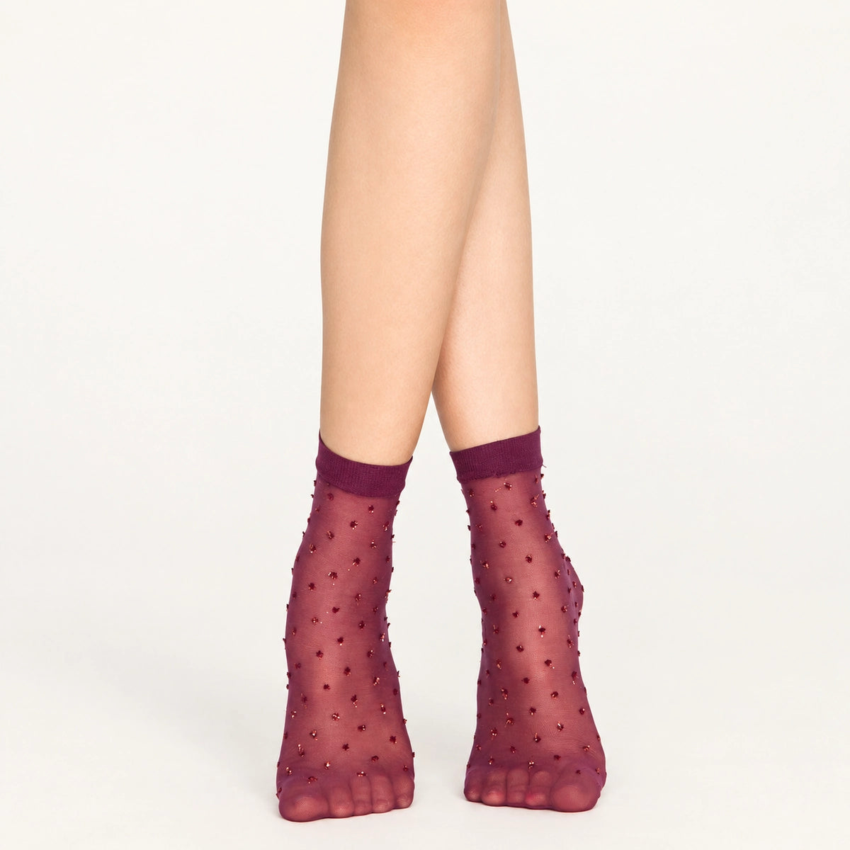 Woman wearing sheer amethyst ankle socks with gold dots on white background