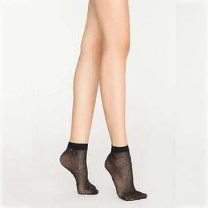 Woman wearing sheer black ankle socks with sparkling dots on white background