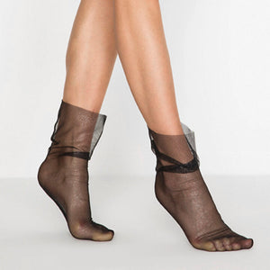 Women's black sheer mesh ankle socks with a subtle silver shimmer and a loose, slouchy fit on model's legs.