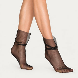 Women's black sheer mesh ankle socks with a subtle silver shimmer and a loose, slouchy fit on model's legs.