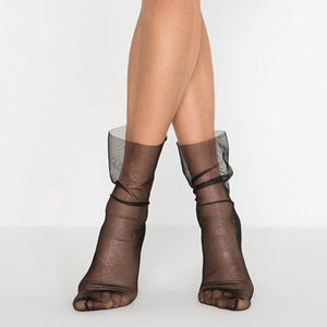 Women's black sheer mesh ankle socks with a subtle silver shimmer and a loose, slouchy fit on model's legs.