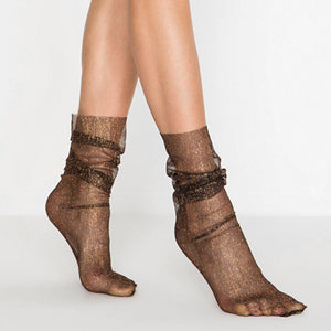 Women's black sheer mesh ankle socks with glittering gold shimmer and a loose, ruched fit on model's legs.
