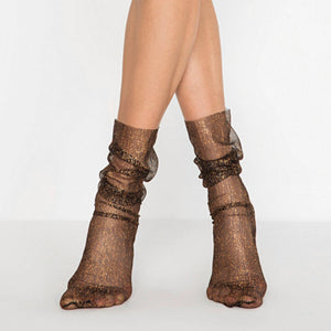 Women's black sheer mesh ankle socks with glittering gold shimmer and a loose, ruched fit on model's legs.