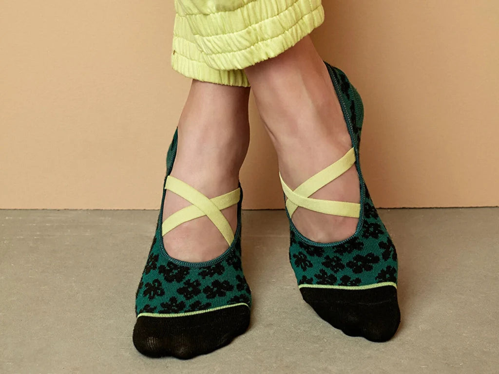 The feet of a woman wearing green, black and yellow yoga and pilates socks