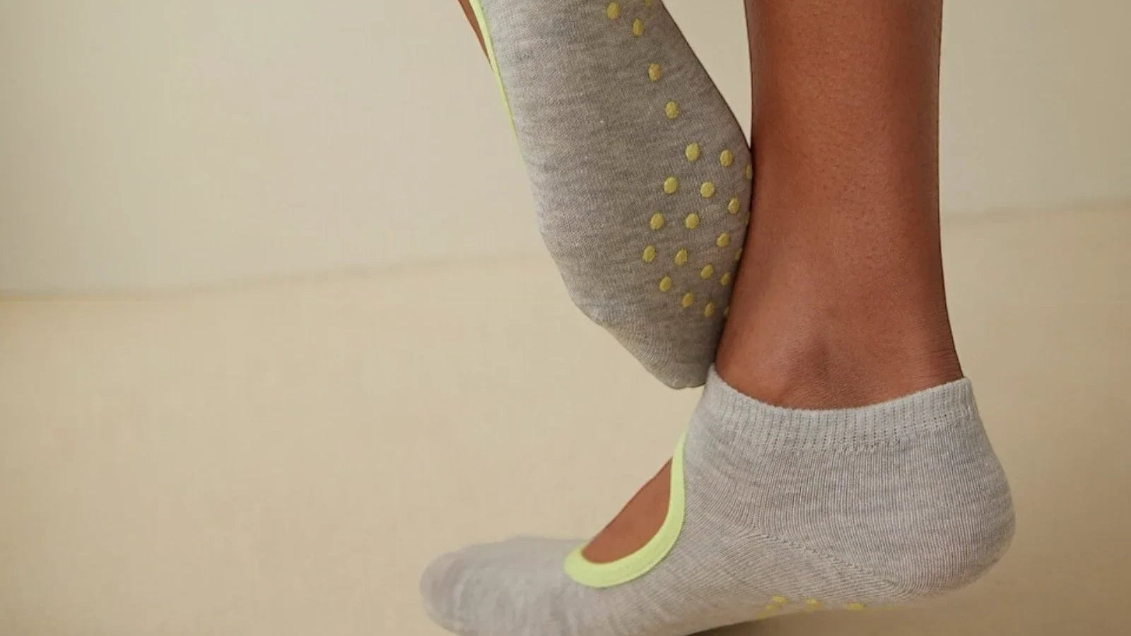 Close-up of a grey Uniq Socks studio sock with yellow silicone grip dots on the sole