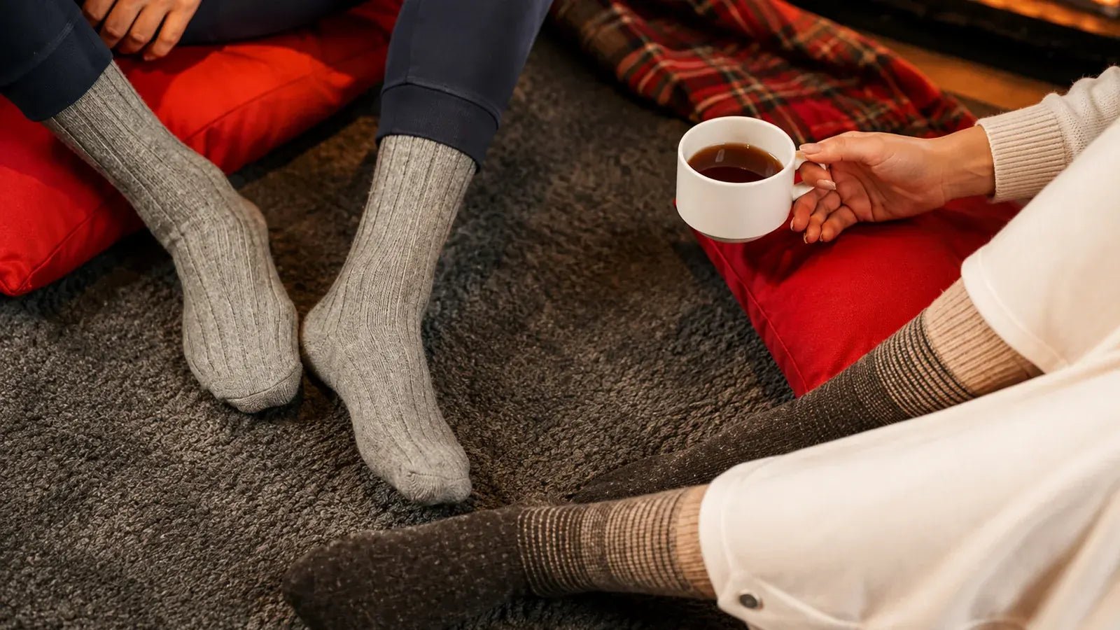 Two people wearing warm ribbed socks in a cosy indoor winter setting