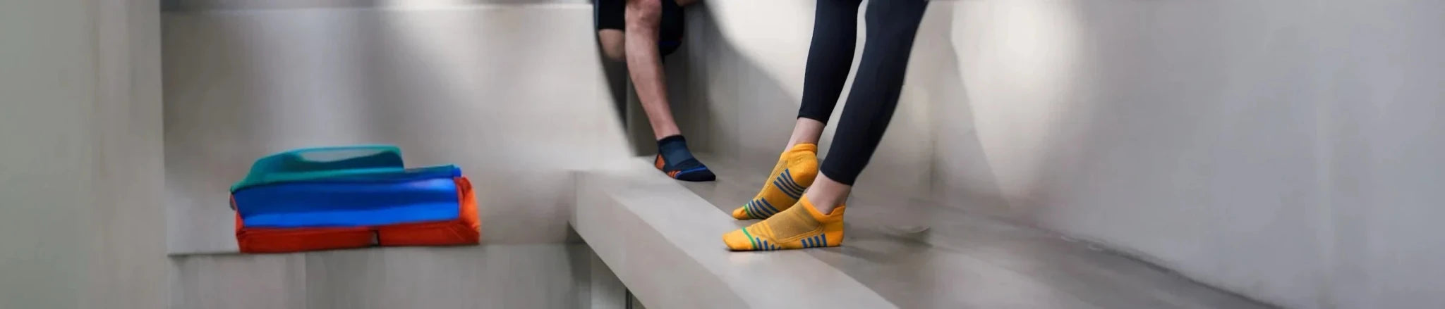 Two people standing on a bench wearing activewear and sneaker socks