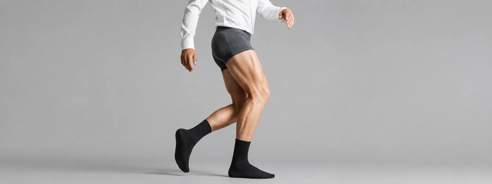 Luxury black business socks styled with a crisp white shirt in a clean light grey studio setting.