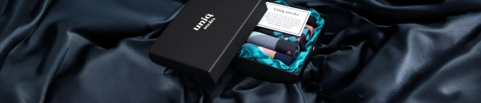 A black giftbox with multicoloured socks against a dark background