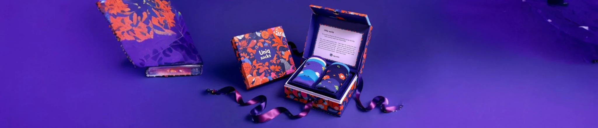An orange themed giftbox filled with multicoloured socks against a purple background