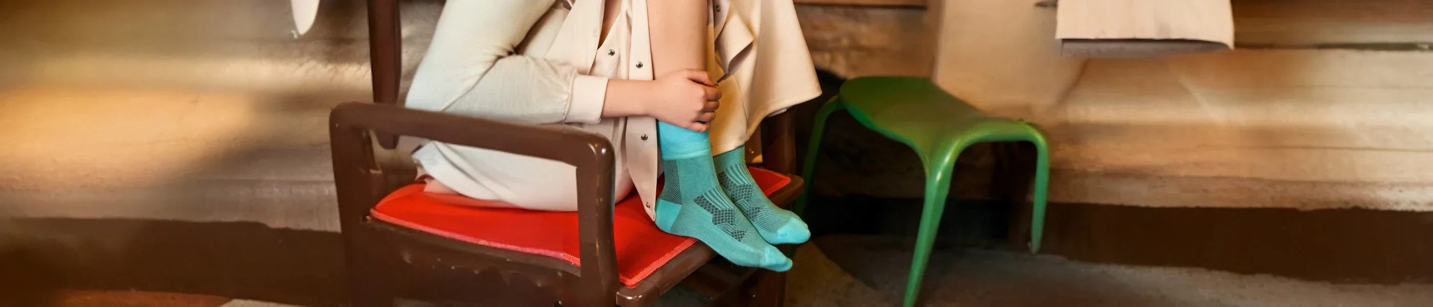 A woman wearing aqua crew socks sitting on a red chair in a lounge room