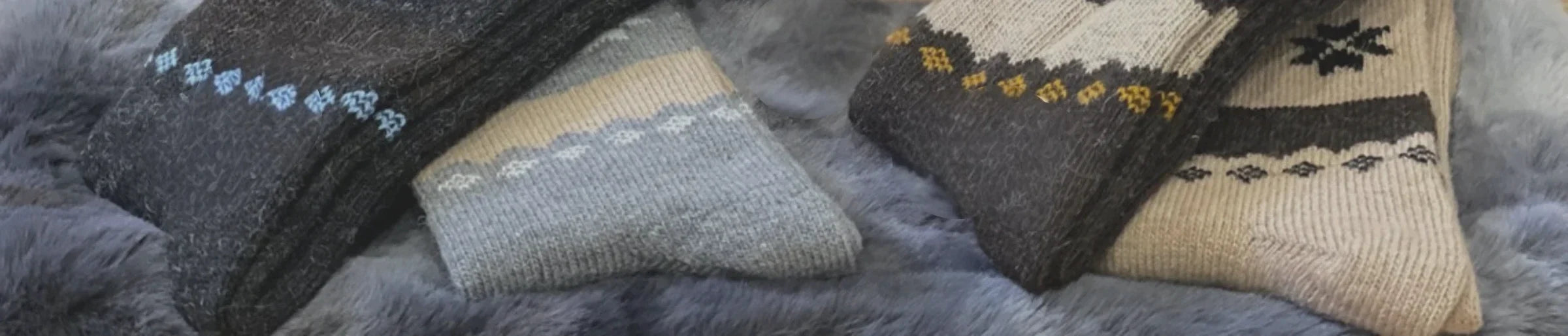 Four pairs of winter socks in grey, beige, and brown patterns against a grey background