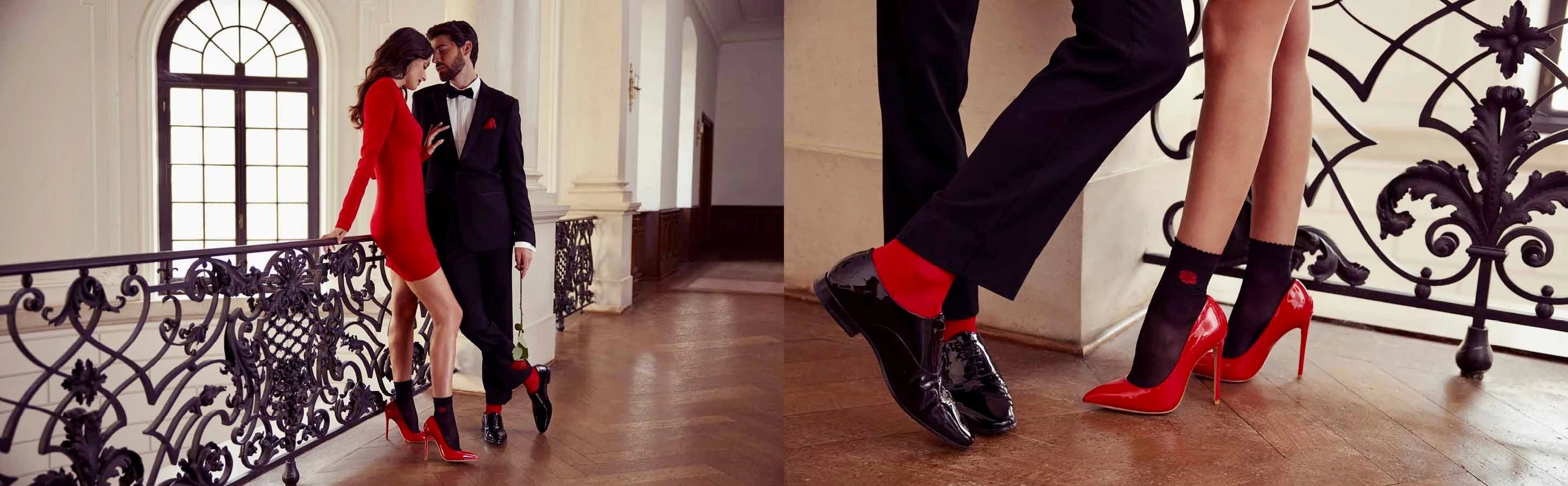 Man and woman wearing red themed dress outfits standing on a timber floor near a white staircase with black wrought iron railing