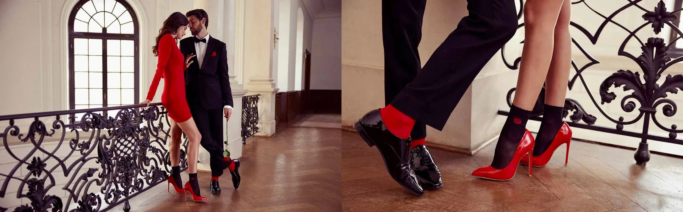 Man and woman wearing red themed dress outfits standing on a timber floor near a white staircase with black wrought iron railing