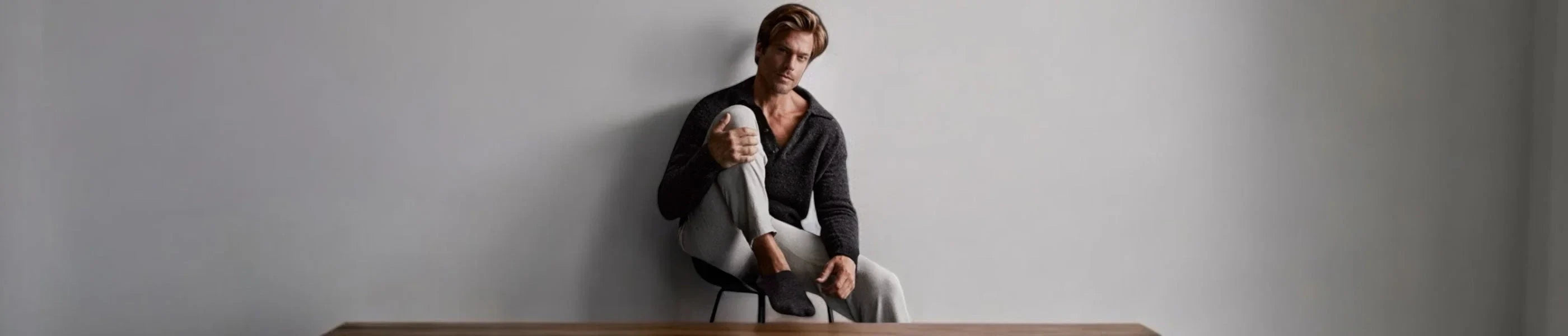 A man wearing no-show socks with a grey outfit against a grey background