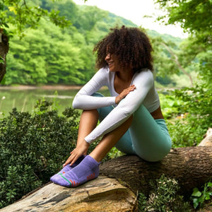 Woman wearing purple bamboo sneaker sock with orange stripes