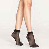 Woman wearing sheer black ankle socks with sparkling dots on white background