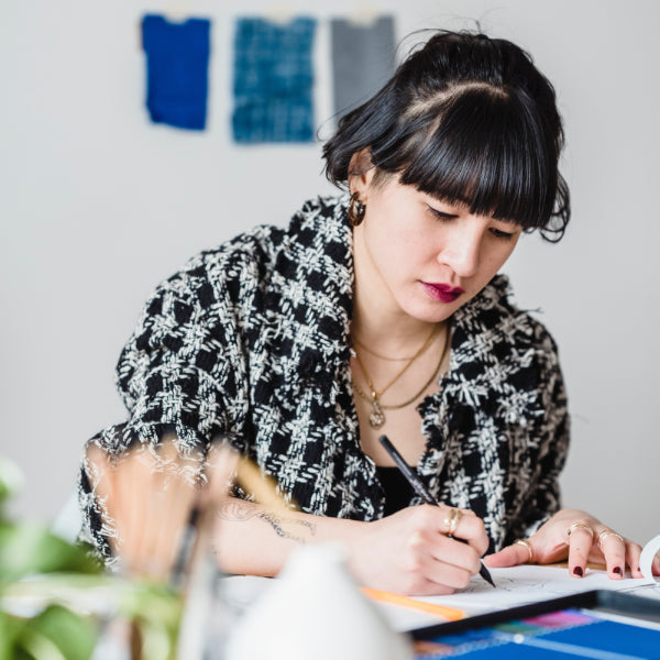 image of a woman sitting at a desk drawing a design