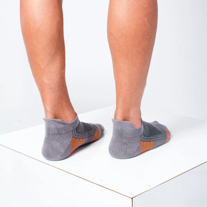 man wearing grey bamboo athletic socks with orange and blue stripe