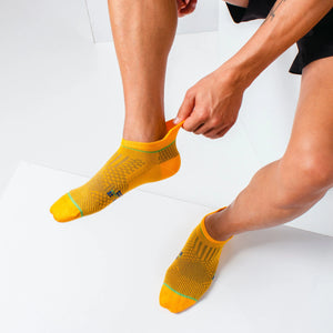 Man wearing orange athletic sock for running and golf with heel tab