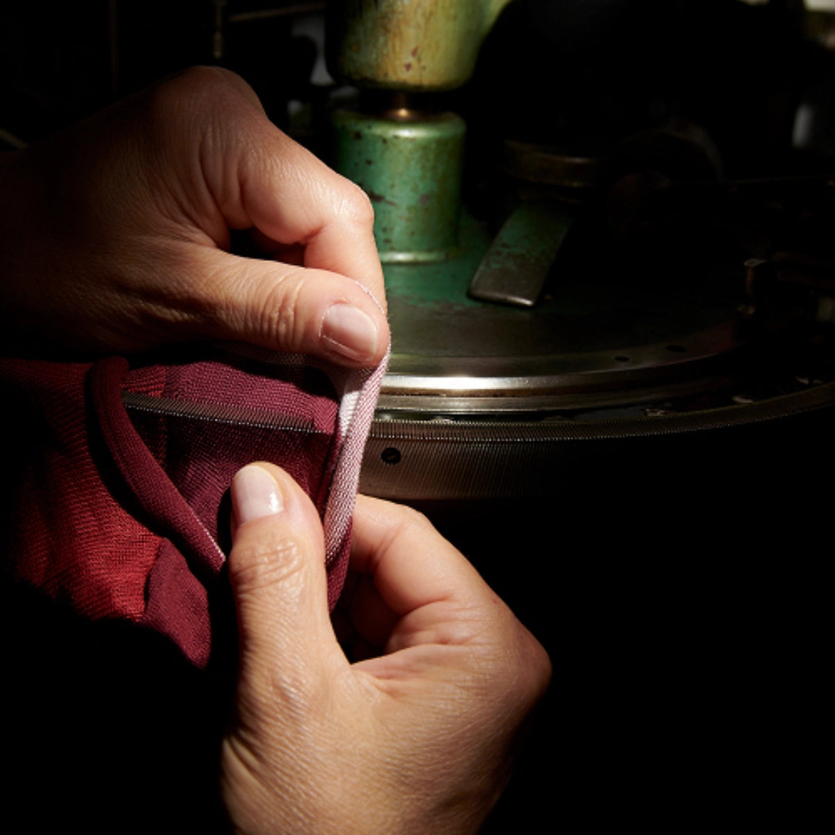 Close-up of hands sewing fabric with a dark background