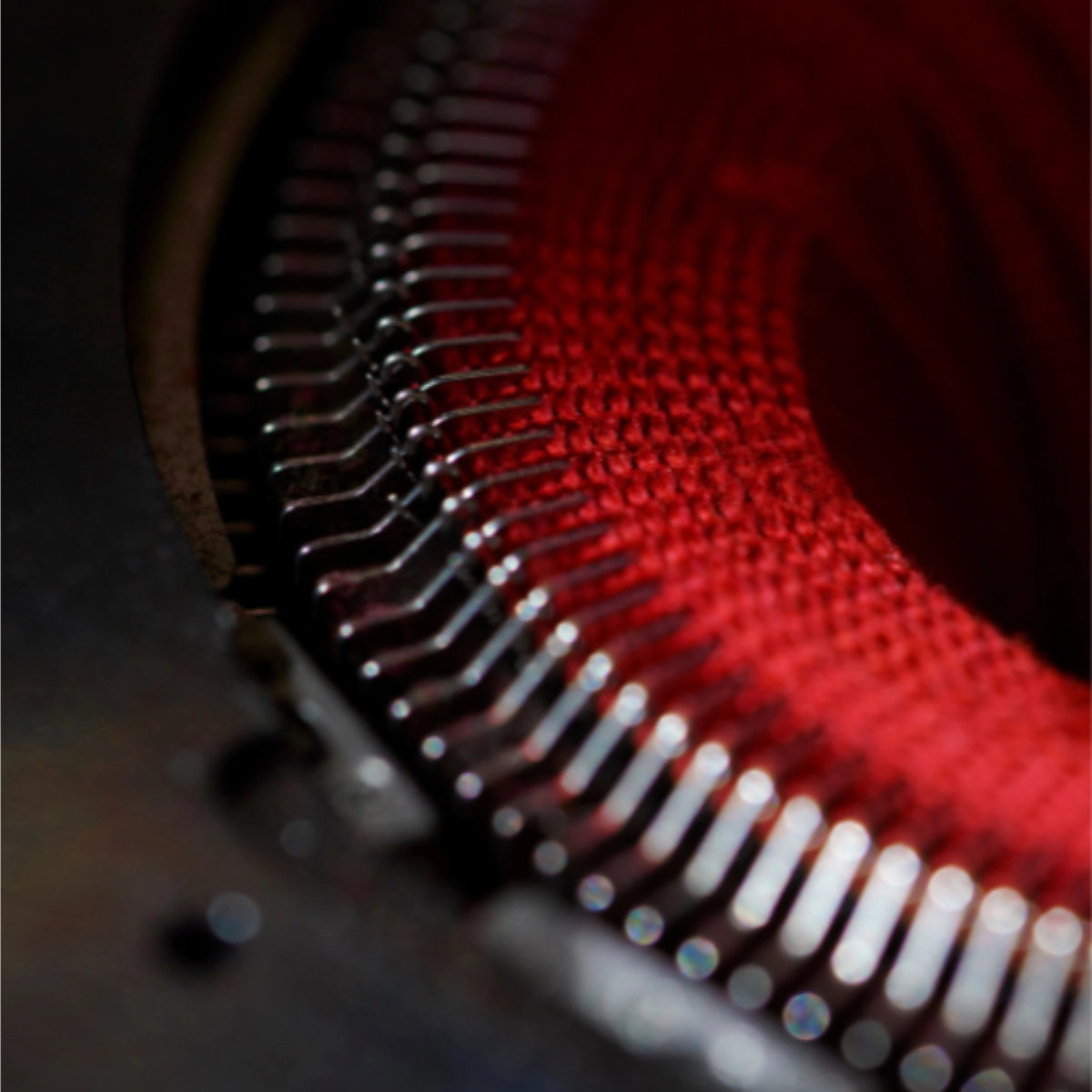 Close-up of a sock knitting machine producing a red sock