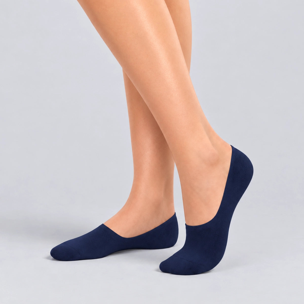 Person wearing navy bamboo no-show socks on a white background