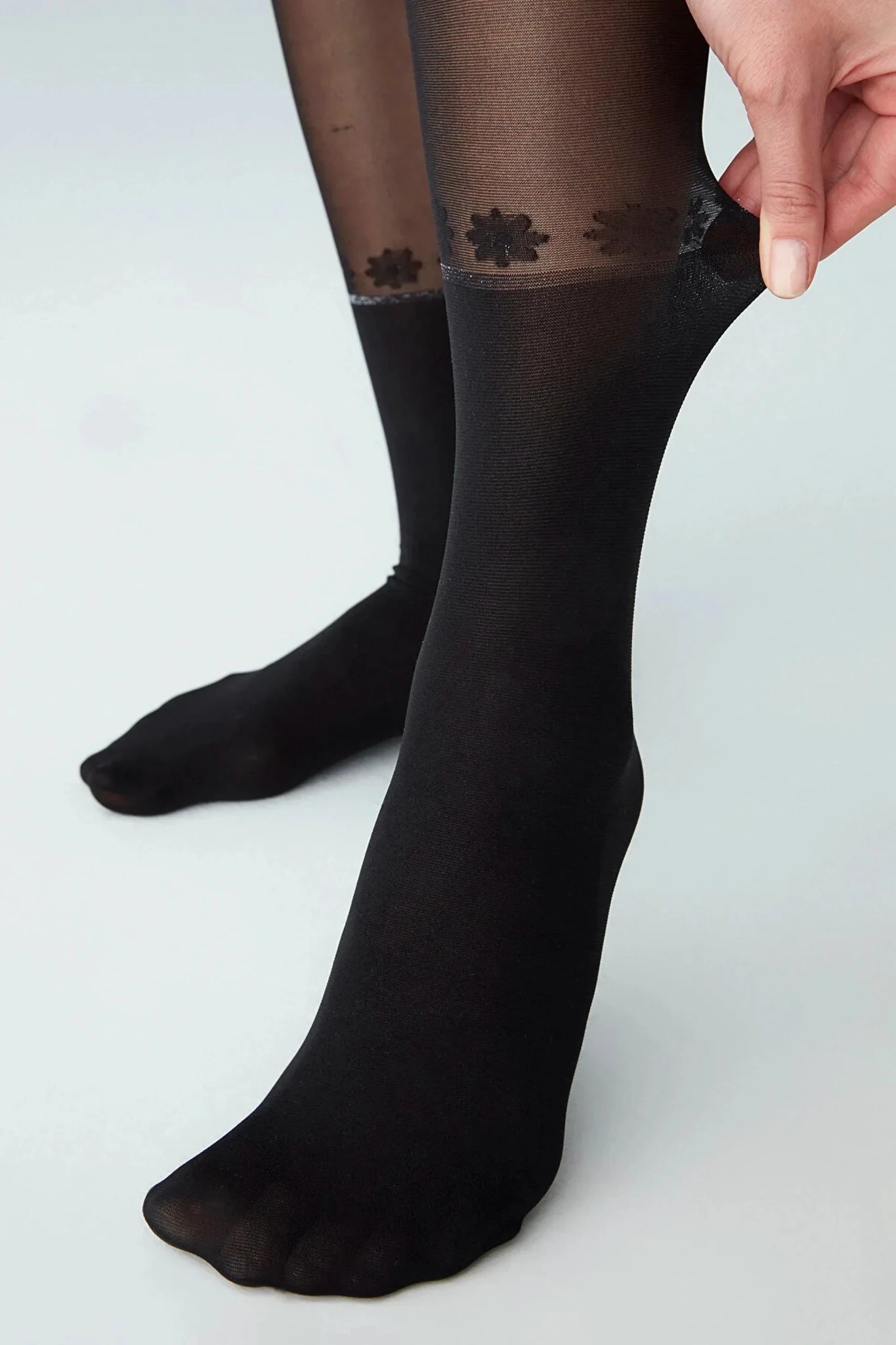 Woman wearing black 30DEN sheer tights with a white daisy pattern resembling a crew sock.