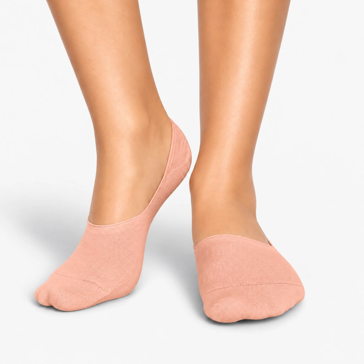Person wearing salmon bamboo no-show socks on a light grey background