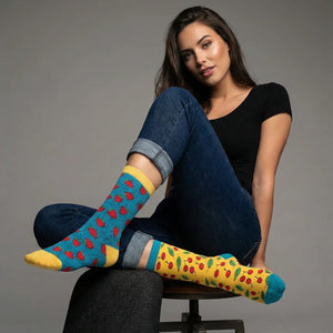 Woman wearing cherry themed socks sitting on a chair against a grey background