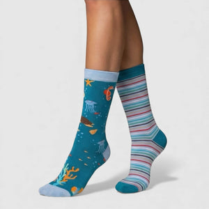 Colourful mismatched socks with marine design and striped pattern on a plain background