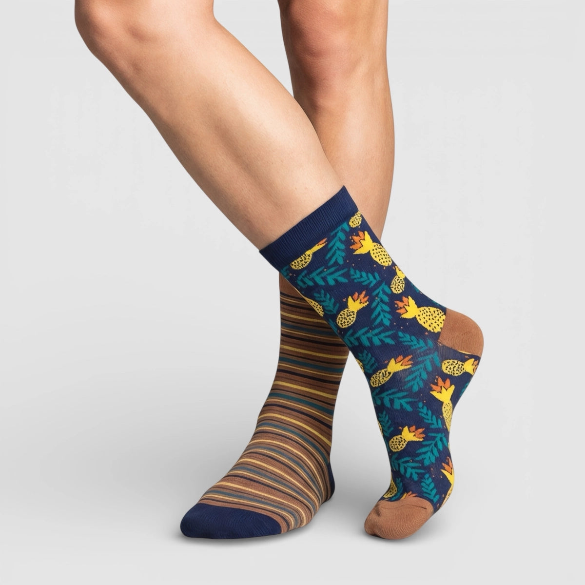 Mismatched socks, one with a striped pattern and the other with a pineapple design, on a light grey background.