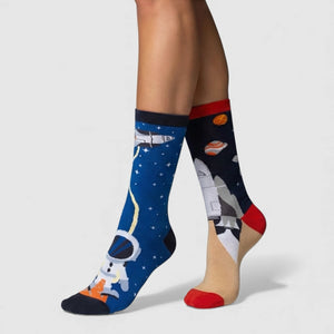 Mismatched space-themed socks with astronauts and rockets on a plain background