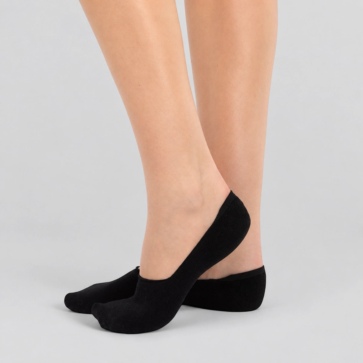 Person wearing black bamboo no-show socks on white background