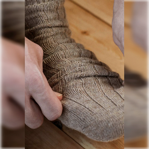 A man putting on plain, beige, alpaca and merino wool socks