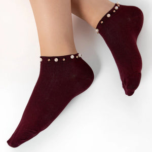 A woman wearing burgundy ankle socks embellished with pearls around the cuff